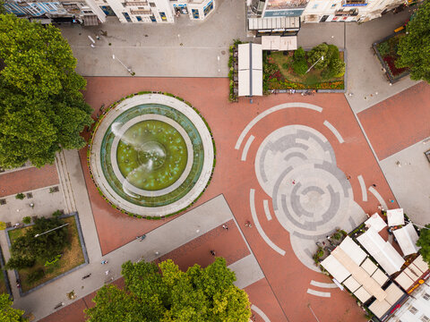 Aerial view of the central square in Varna featuring a circular fountain, paved walkways, and outdoor seating areas in Varna, Varna, Bulgaria.