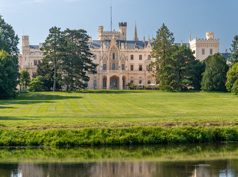 A view of Lednice Castle in the Czech Republic. A neo-Gothic castle in Moravia surrounded by a park. A historic park and garden in summer. Flowering plants in the park.