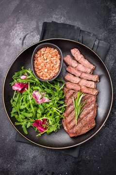 Grilled Top blade steak with salad, beef shoulder meat on a plate. black background. top view
