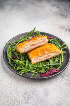Fried Cordon bleu escalopes with salad on plate. white background. top view