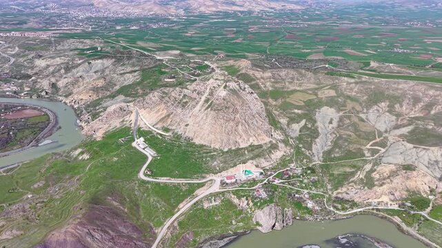 Smooth 4K aerial approach toward Palu Castle during spring, revealing green valleys, open agricultural fields and a clear blue sky in bright daylight.