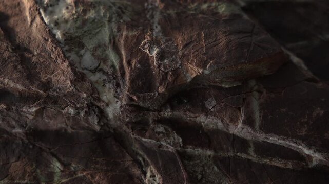 Slow camera movement across dark rugged stone surface