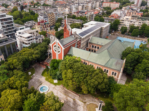 Aerial view of the Evangelical Methodist Episcopal Church surrounded by lush trees, a small fountain, and urban buildings in Varna, Varna, Bulgaria.