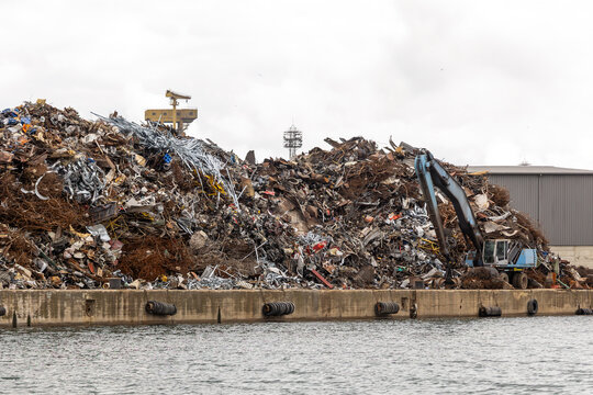  Massive Scrap Metal Pile at Industrial Port with Excavator Loading Recyclable Waste at Harbor Dock