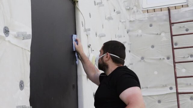 homeowner wearing a respirator cleaning an old steel entrance door with cloth and solvent before painting, showing surface degreasing and safe renovation preparation