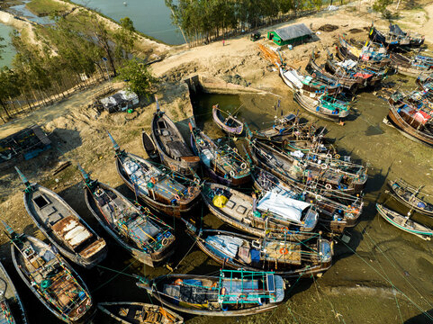 Aerial view of wooden fishing boats docked in the muddy harbor of Moheskhali Upazila, Chittagong Division, Bangladesh.