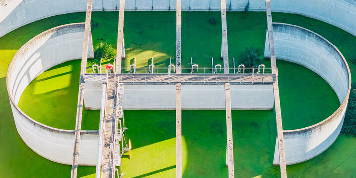 Aerial view of a green wastewater treatment basin with concrete channels and industrial infrastructure for water processing in Valence, Auvergne-Rhone-Alpes, France.