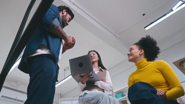 Confident corporate team collaborating on a project, with a male manager pointing at documents while discussing ideas with colleagues.