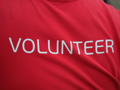 man in  red T-shirt with the words "VOLUNTEER" written on it in white, which is typically used as equipment or uniform at various events, charity events, and sporting competitions.