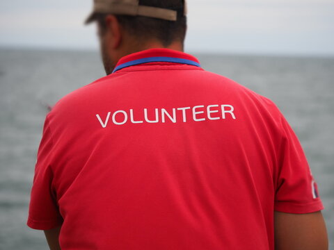 man in  red T-shirt with the words "VOLUNTEER" written on it in white, which is typically used as equipment or uniform at various events, charity events, and sporting competitions.