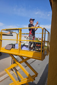 Real senior professional painter aged 63&ndash;66 working on a residential building from an elevated platform