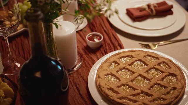Baked lattice pie, wine bottle and festive Thanksgiving dinner table setting captured from high angle view. Clip ideal for seasonal culinary advertising and holiday food marketing campaigns