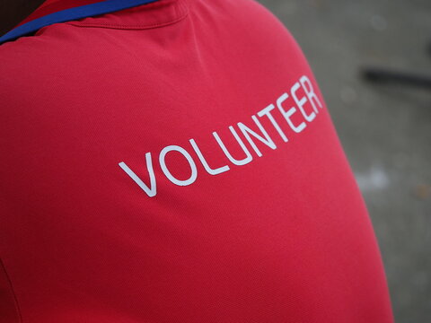 man in  red T-shirt with the words "VOLUNTEER" written on it in white, which is typically used as equipment or uniform at various events, charity events, and sporting competitions.