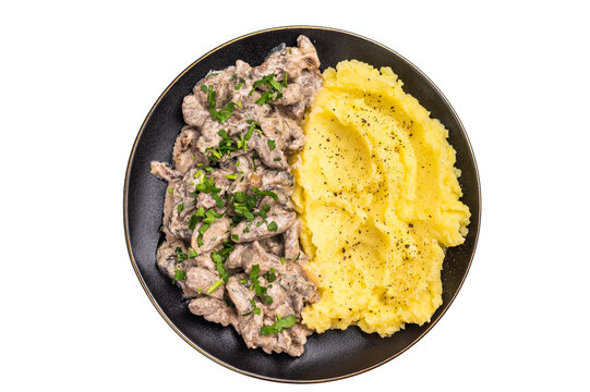 Beef stroganoff with mashed potatoes, fresh greenery and savory mushroom sauce in a plate isolated on white background. top view