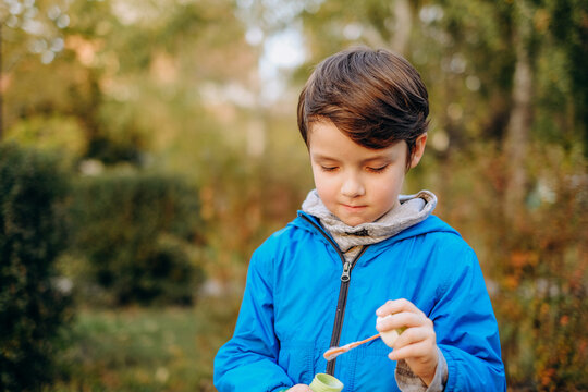 Little boy blowing soap bubbles outdoors in autumn park stock photo