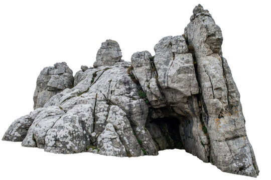 Large jagged limestone rock formation with a dark natural cave entrance isolated on a transparent background
