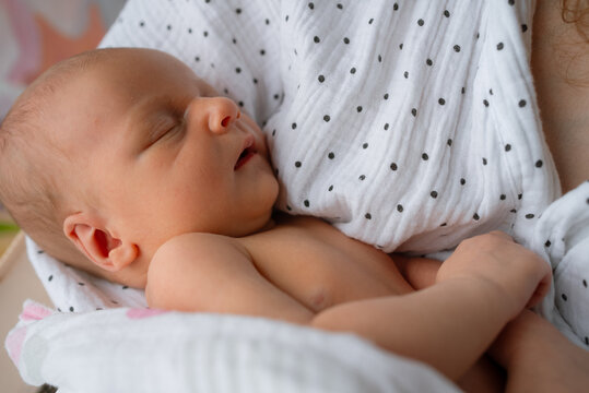 Newborn baby sleeps deeply, embraced by a mother's warm, supportive arms, creating an intimate connection illustrating maternal bond, early childhood, and the start of a family journey