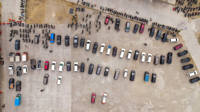 Aerial view of Waisai Harbour parking lot filled with numerous cars and motorcycles parked in organized rows under daylight, Raja Ampat, Papua Barat Daya, Indonesia.