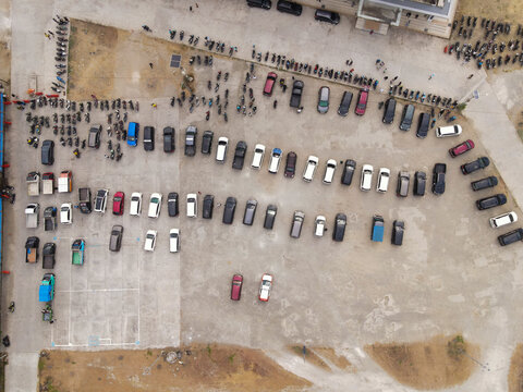 Aerial view of Waisai Harbour parking lot filled with numerous cars and motorcycles parked in organized rows on a concrete surface. Raja Ampat, Papua Barat Daya, Indonesia.