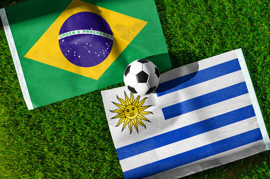 Brazil vs Uruguay football and soccer match background concept showing national flags on green grass field for South American rivalry