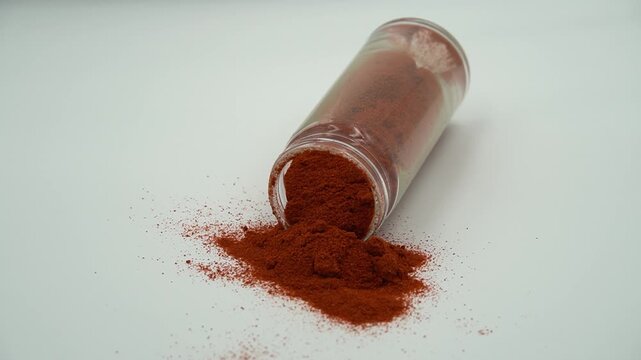 Spilled Red Spice Powder from a Glass Shaker Isolated on White