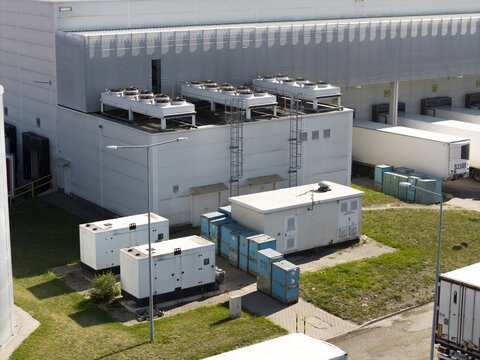 Aerial view of an AI data center cooling system with rooftop fans, backup generators, and loading docks at a facility in Poland.