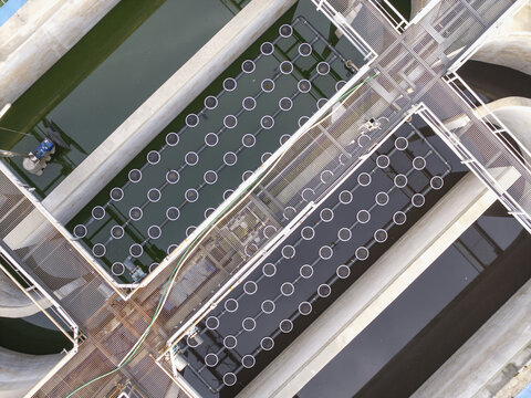 Aerial view of a wastewater treatment facility with circular aeration diffusers and metal walkways in Poland.