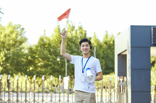 Young male tour guide with red flag and megaphone outdoors