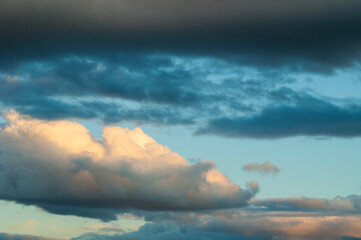 Obraz premium Dramatic sky background. Layers of dark blue clouds at the top and sides. A bright golden cloud formation glowing with sunlight