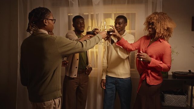 African American young adult friends toasting wine glasses celebrating Thanksgiving indoors in slow motion. Footage suits holiday lifestyle commercials and beverage marketing campaigns