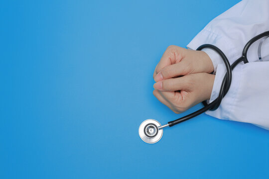 Doctor displays deep integrity with bound hand by black stethoscope against blue background facing heavy medical stress with anxious mood