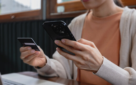 Close up woman holding credit card and using smartphone for online shopping. Mobile payment concept