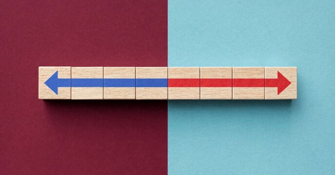 Conceptual image of opposing wooden blocks with blue and red arrows pointing in reverse directions on split color background