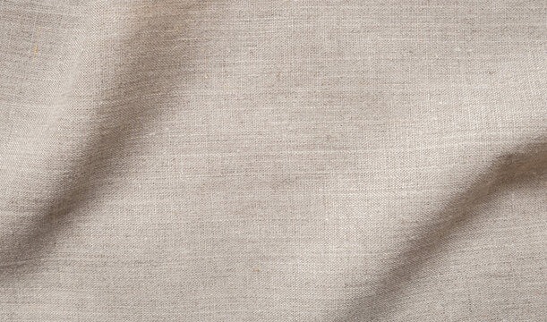 Natural beige linen fabric texture background with soft waves, beautiful cloth pattern surface for design overlay and backdrop material.