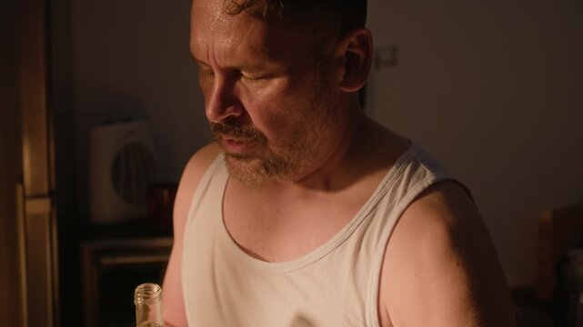 Middle aged Caucasian man opening glass bottle, refreshing face with liquid, and drinking water. Clip suitable for addiction awareness, mental health, and therapy campaigns