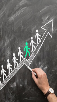 Chalk figures ascend an upward arrow on a blackboard, symbolizing progress, growth, and leadership in business. Free space for text.