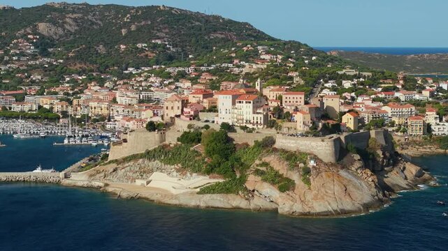 Calvi Corsica drone 70mm telephoto citadel fortress mountain background marina orbit turn, historic stone citadelle reveal dramatic compression