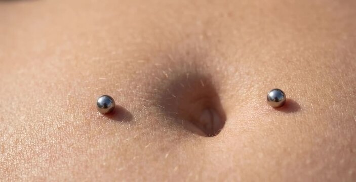 Macro Close Up of Double Surface Silver Ball Navel Piercing on Flat Belly