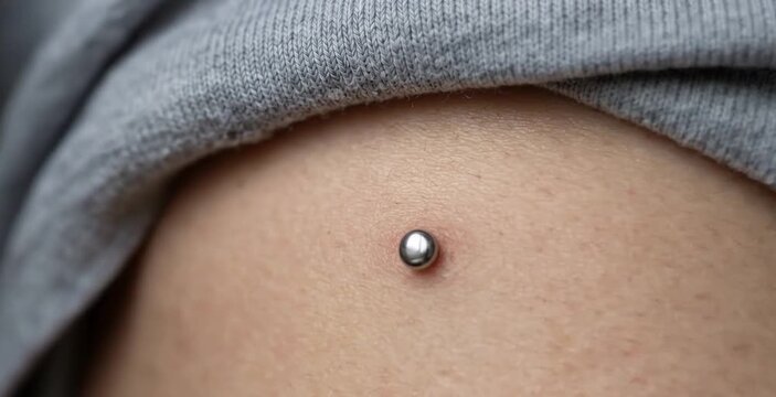Macro Close Up of Single Silver Ball Microdermal Anchor Piercing on Woman Skin