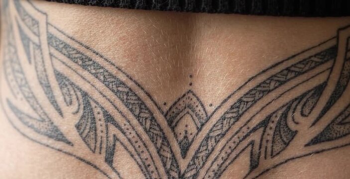 Close Up of Symmetrical Ornamental Tribal Mandala Tattoo Across Woman Lower Back