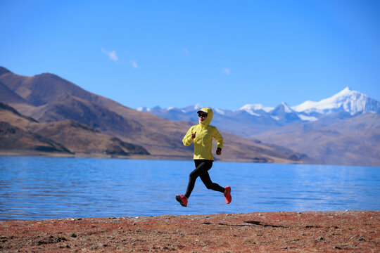 Woman runner running at the winter high altitude lakeside, Tibet