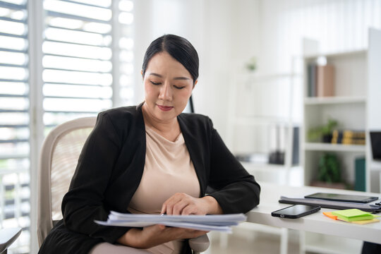  businesswoman auditing revenue report and planning budget while working at desk in office.