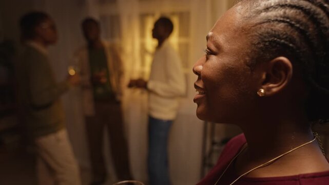 African American young adult woman holding wine glass talking during Thanksgiving celebration with friends. Clip perfect for holiday commercials, wine branding, social lifestyle campaigns