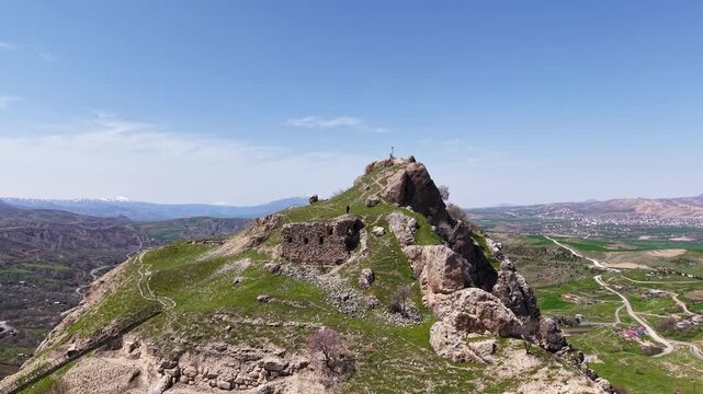 Fast and smooth 4K aerial pullback from ancient ruins, moving straight backward to reveal the surrounding mountain landscape and historic stone structures.