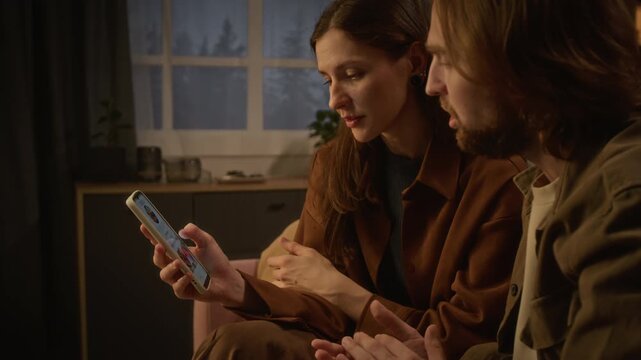Caucasian young couple browsing food delivery application on smartphone, discussing dinner options. Perfect for mobile app promotion, online ordering commercials, digital marketing