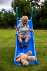Obraz premium Child slides with teddy outdoors.