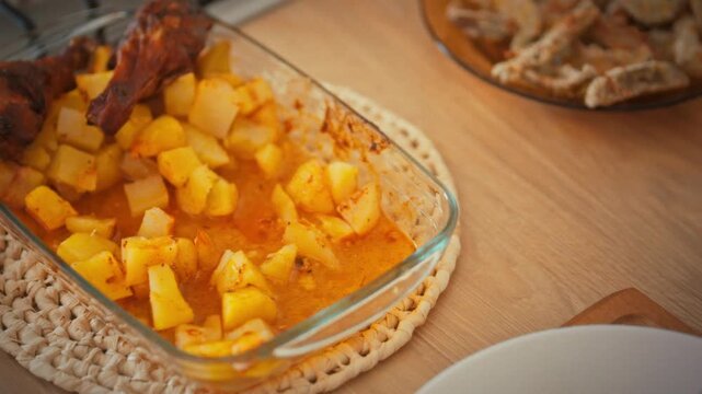 Serving roast meat and baked potatoes. A housewife arranges food on a plate in a home kitchen with a large countertop. A family Thanksgiving theme in a family setting