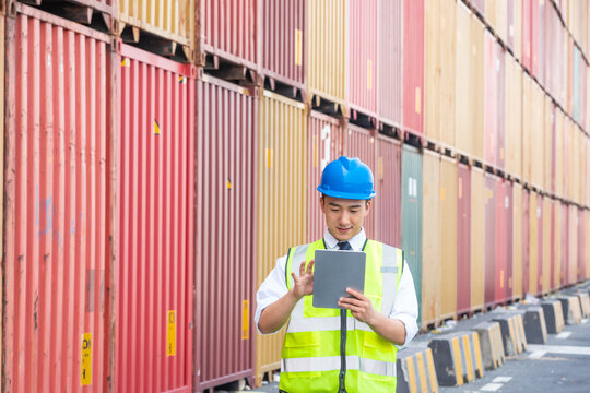 Logistics worker with tablet in shipping container yard