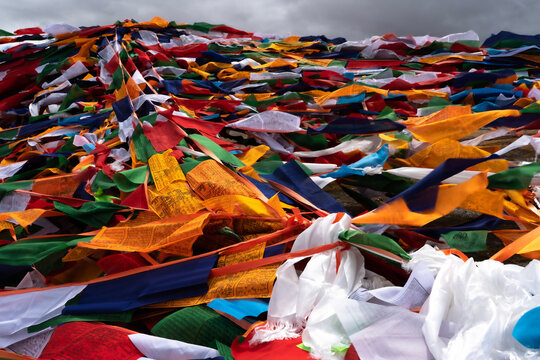 Dense pile of colorful Tibetan prayer flags fluttering under overcast sky in Tibet
