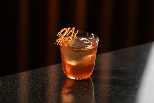 Amber cocktail with caramel cage garnish on sphere ice glass